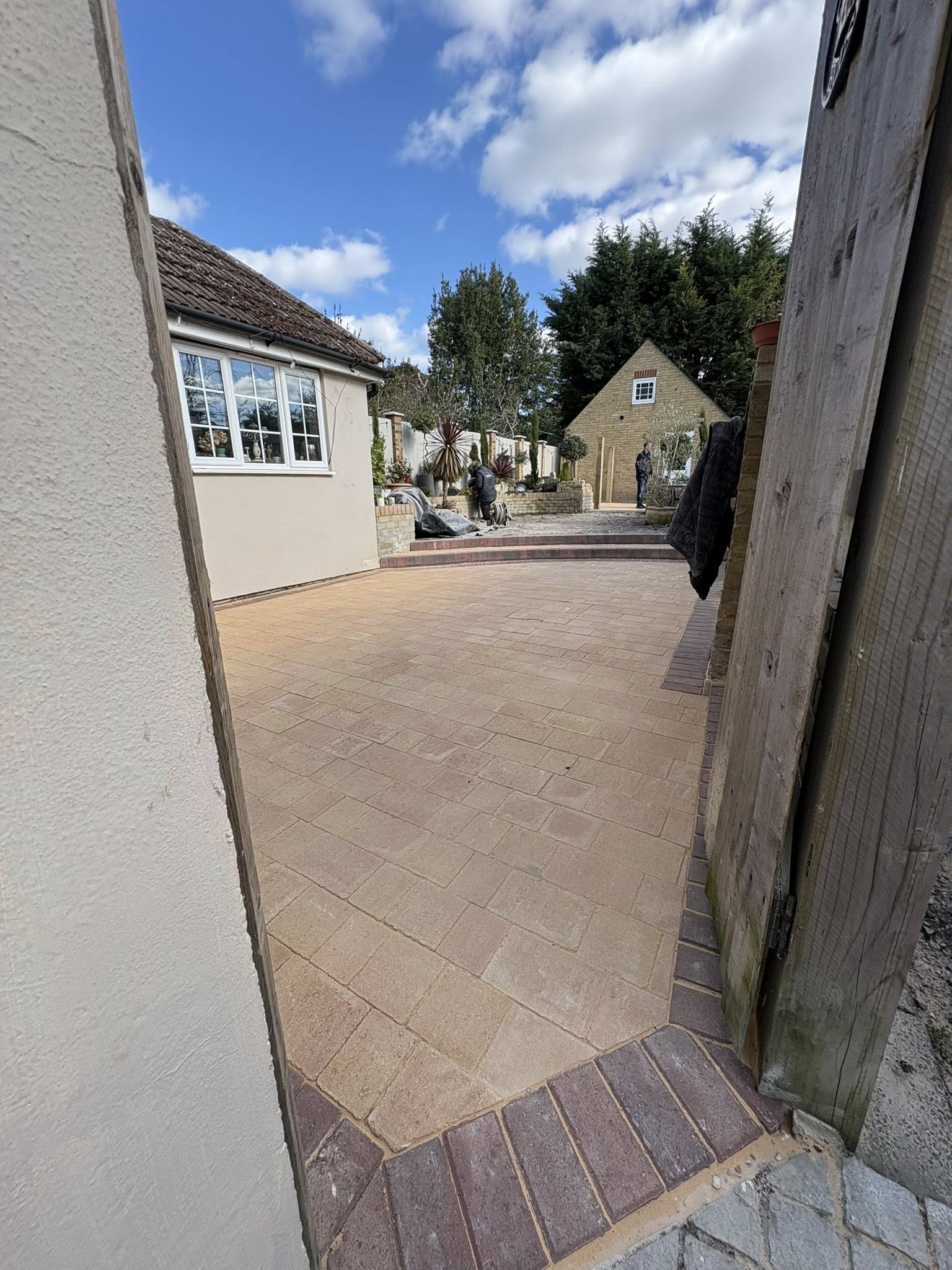 View through side gate to mellow yellow block paving garden at a Victorian semi in Canterbury
