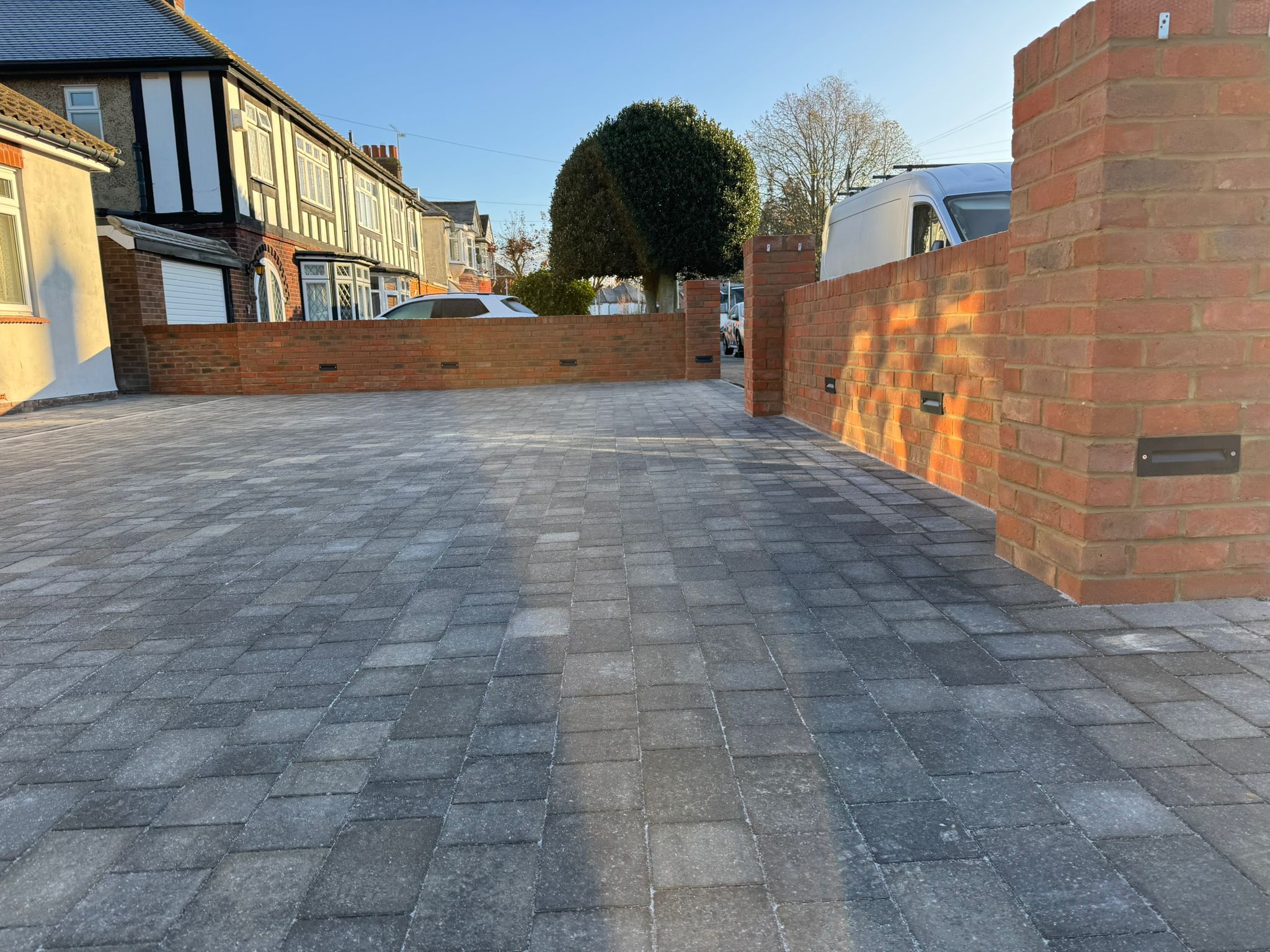 Complete driveway transformation in Rochester: Premium grey block paving with decorative brick retaining walls featuring integrated outdoor lighting for enhanced security and kerb appeal
