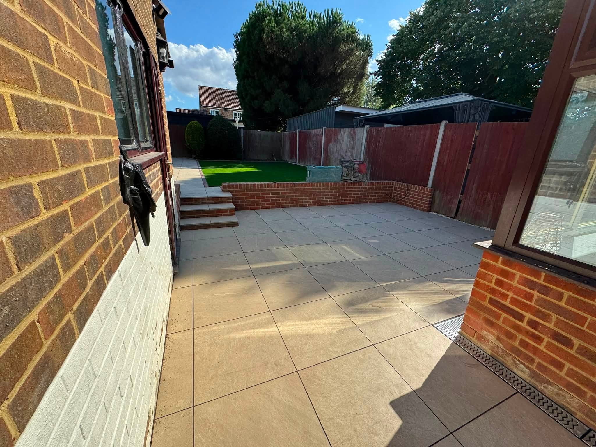 Porcelain patio with an ACO drainage channel along the base of a conservatory in Hempstead