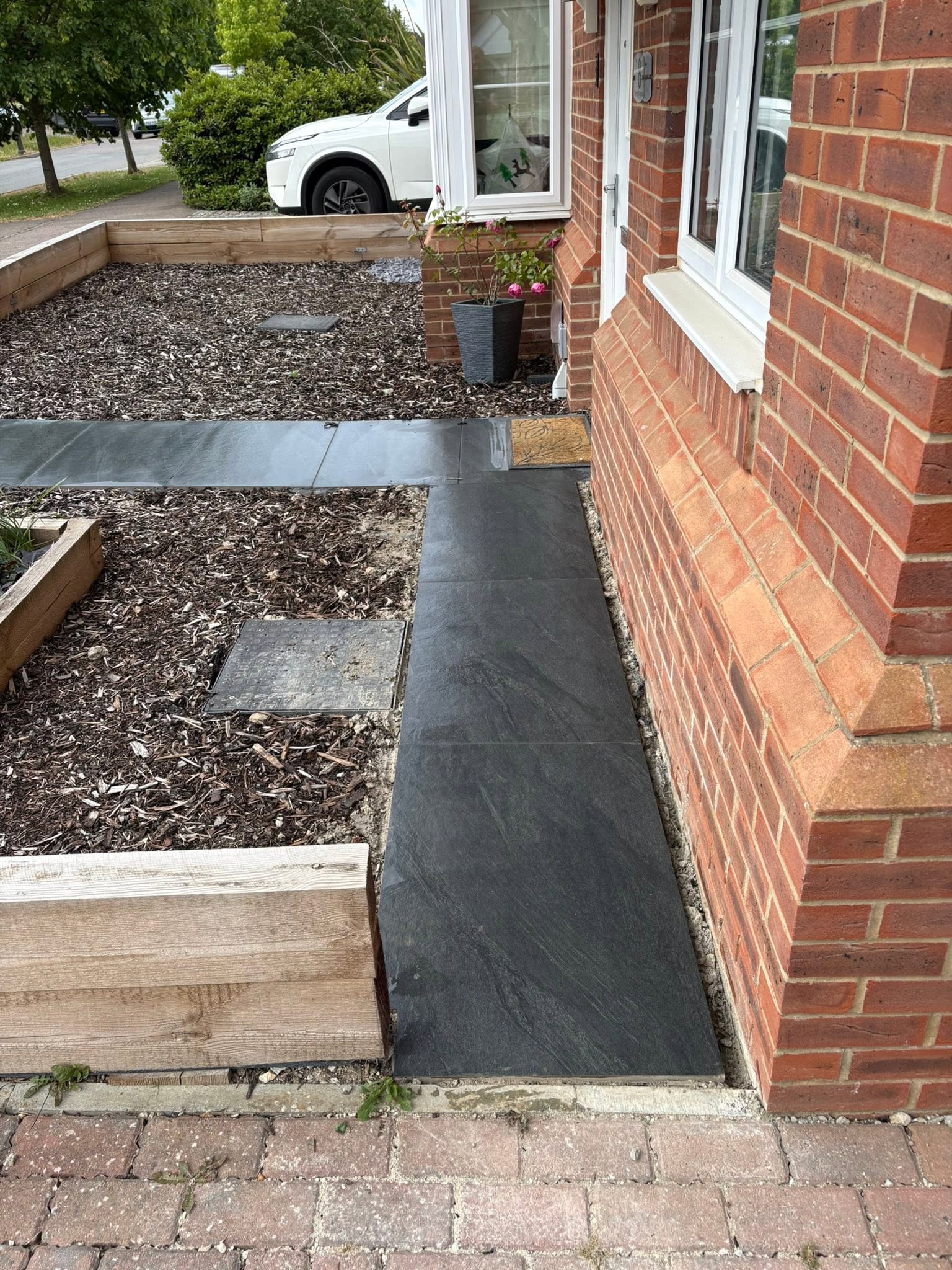 Porcelain paving path detail beside timber sleeper raised beds at the front of a Maidstone house