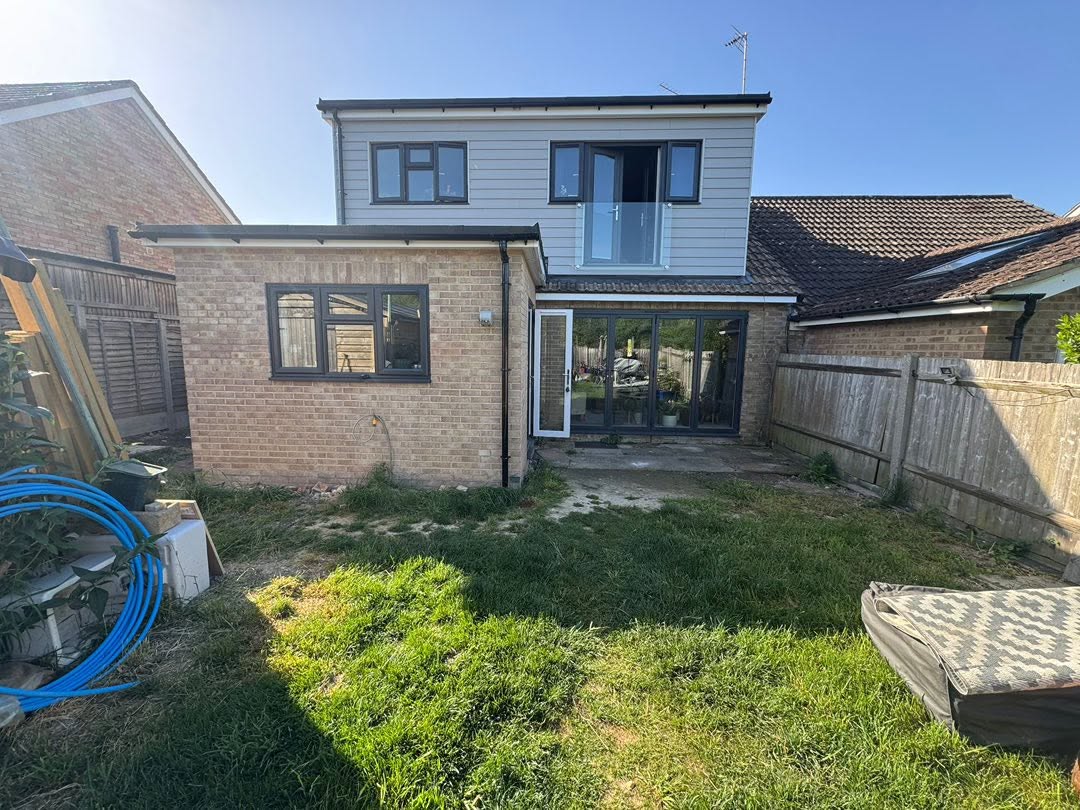 Rear of a Maidstone house before the patio, with bi-fold doors opening onto a cracked concrete strip and uneven lawn