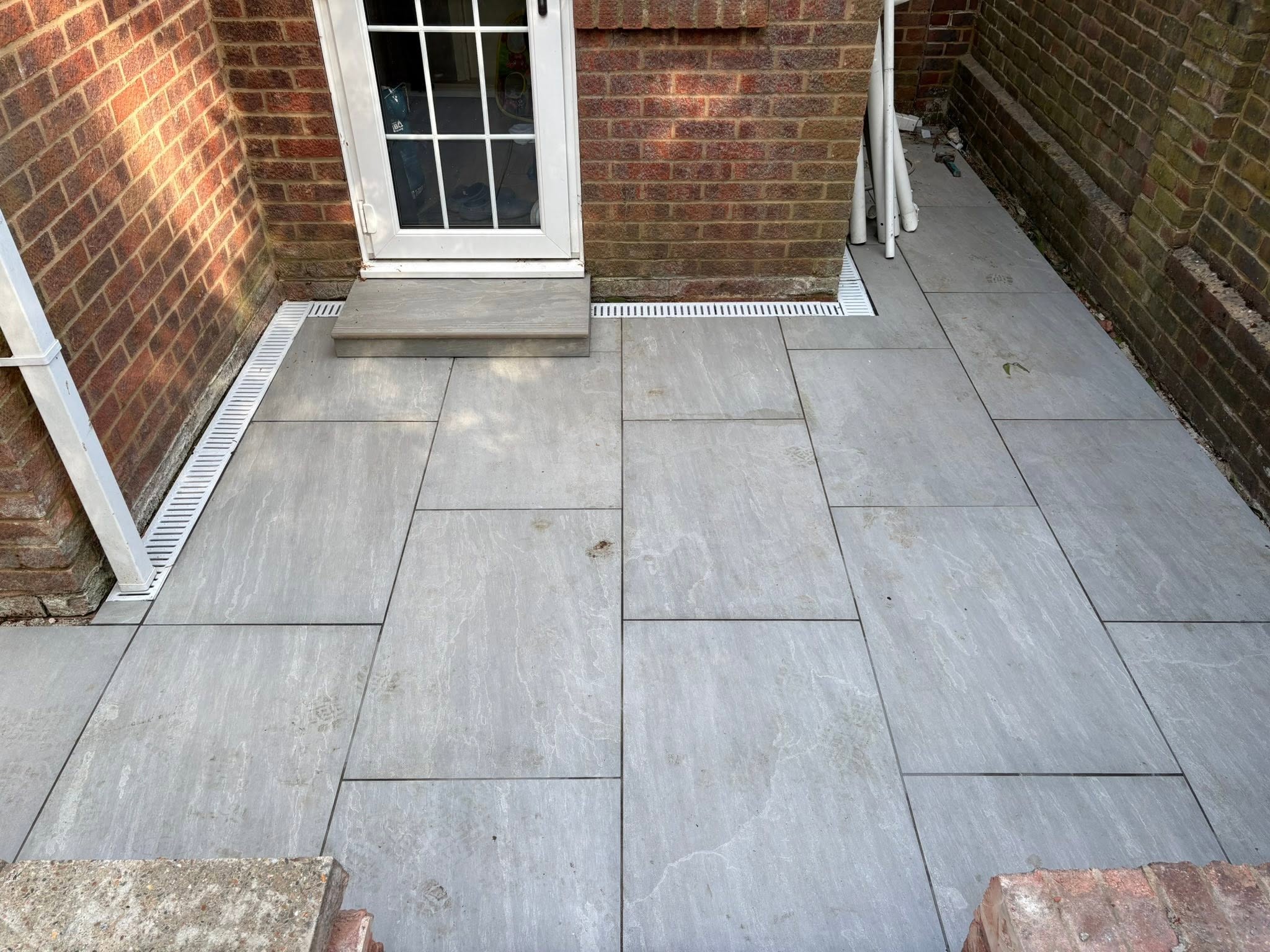 Linear drainage channel set into Kandla Grey porcelain at the French doors of a Medway home