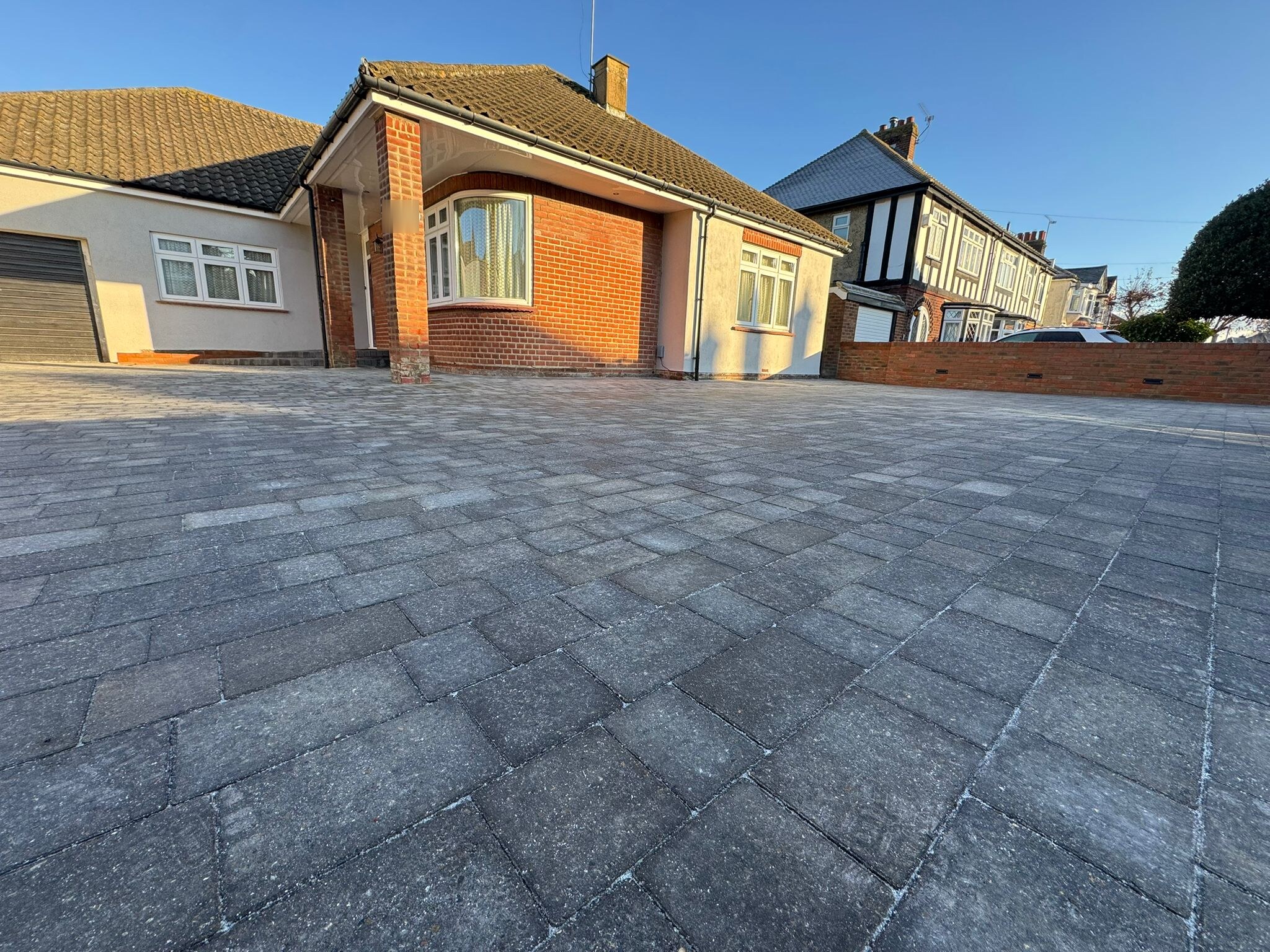 Grey block paving driveway in front of a Rochester bungalow in low evening sun