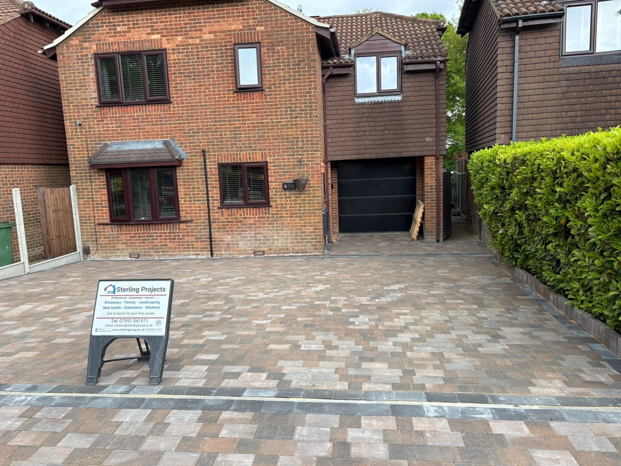 Brett Trio Burnt Oak block paving driveway with charcoal border and black garage door in Sevenoaks