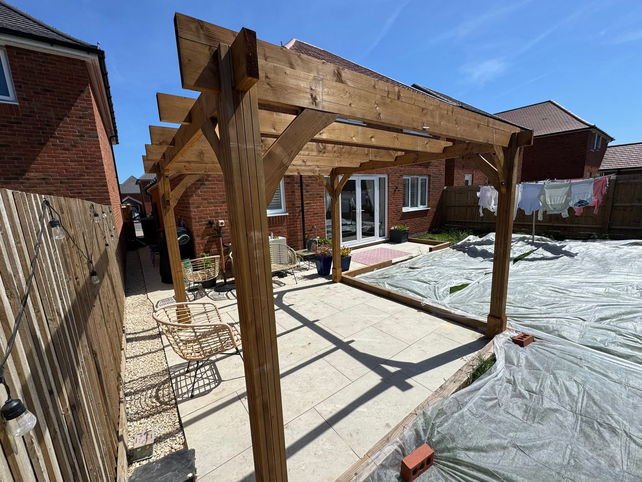 Bespoke timber pergola fitted over a porcelain patio in Sevenoaks creating a shaded seating area