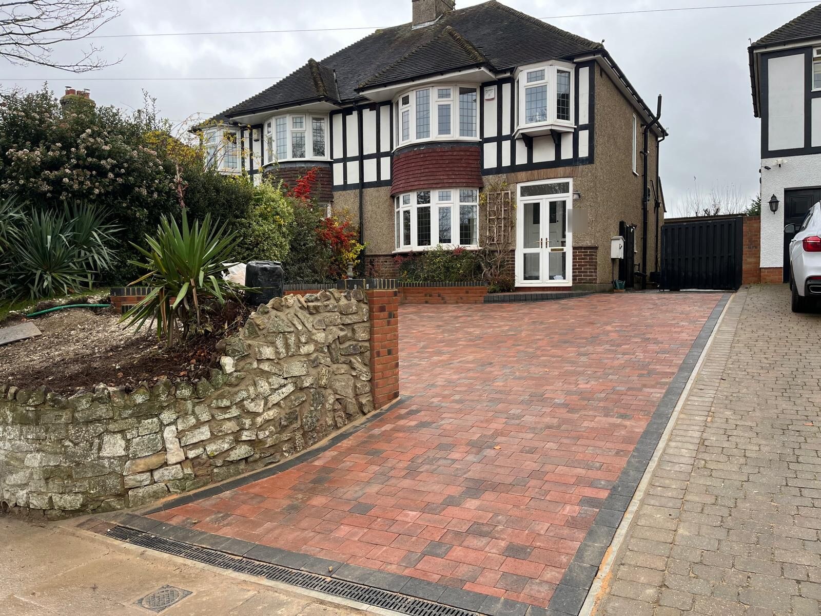 Completed red brick block paving driveway in Rochester with retaining wall and black border